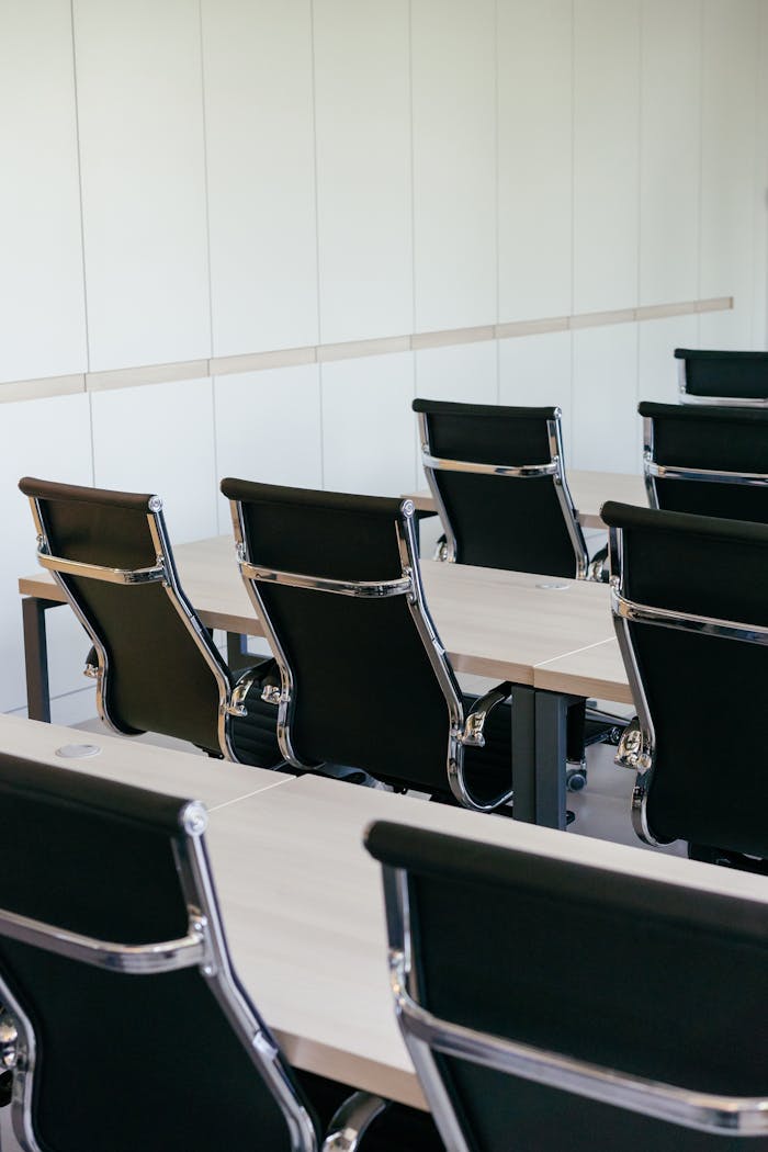 Empty modern conference room with sleek black chairs and wooden desks, perfect for business meetings.